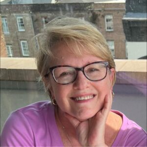 Smiling woman with glasses and short hair.