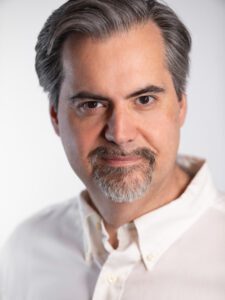 Man with graying hair and goatee smiling.